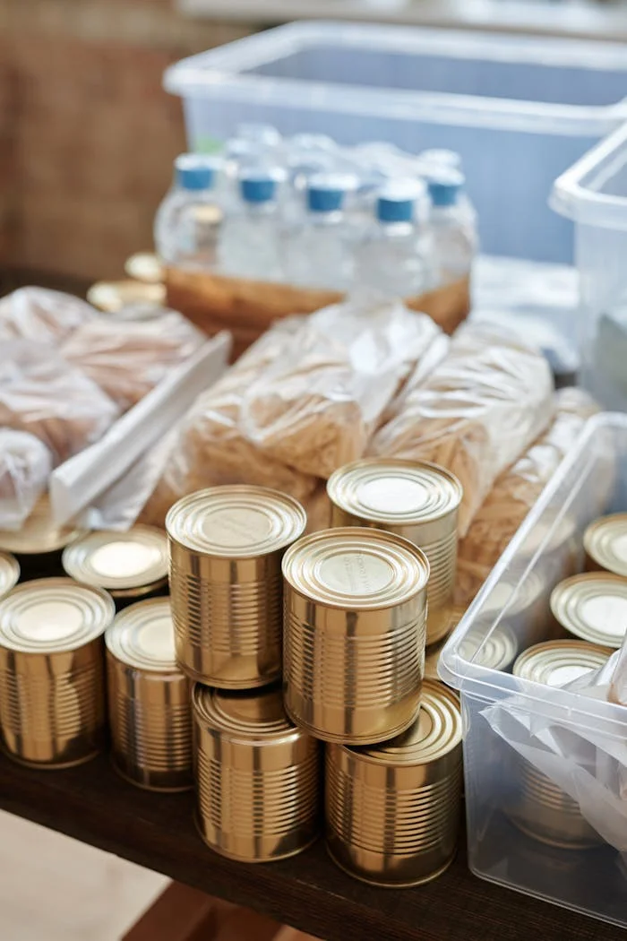 our-experience A variety of canned goods and packaged items arranged for a donation drive or food bank collection.