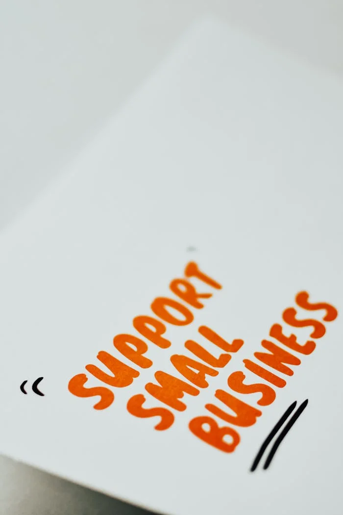 Close-up of a 'Support Small Business' message in orange text on a white paper.